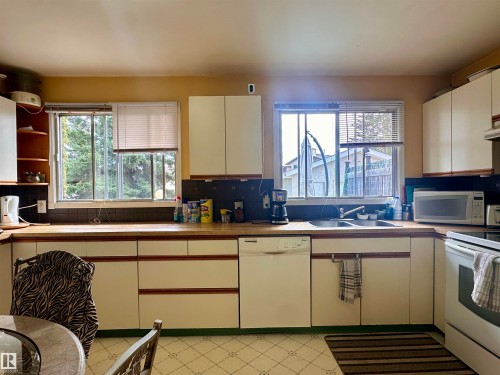 Kitchen featuring white cabinetry with wood-finish trim, wood-finish countertops, and a double basin sink - 10619 108 Avenue, Westlock, AB - Indoor Photo Showing Kitchen With Double Sink