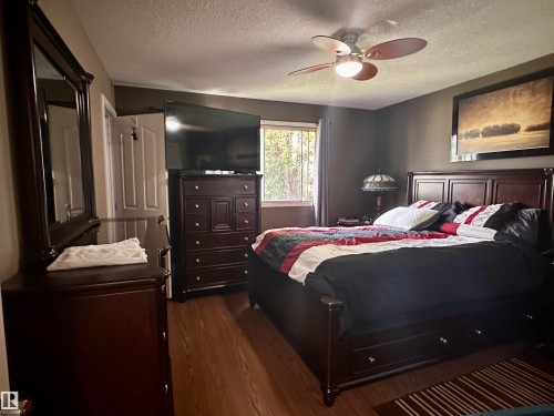 Bedroom featuring wood-finish flooring, a ceiling fan with integrated lighting, and a large window - 10619 108 Avenue, Westlock, AB - Indoor Photo Showing Bedroom
