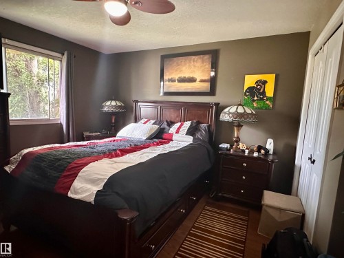 Dark wood-finish flooring with a multi-paned window - 10619 108 Avenue, Westlock, AB - Indoor Photo Showing Bedroom