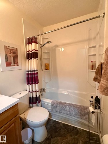 Full-size bathtub with integrated shelving, a wall-mounted showerhead, and a white shower surround - 10619 108 Avenue, Westlock, AB - Indoor Photo Showing Bathroom