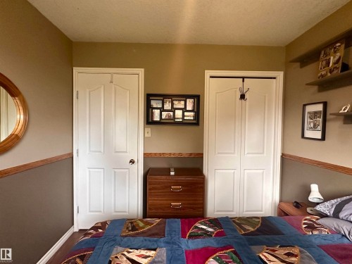 Bedroom featuring a white paneled door, bi-fold closet door, and two-tone wall treatment with wood-finish trim - 10619 108 Avenue, Westlock, AB - Indoor Photo Showing Bedroom