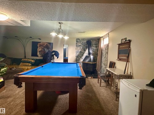 Recreational space featuring a wood-finish pool table, stone accent wall, wood-burning stove, and recessed lighting - 10619 108 Avenue, Westlock, AB - Indoor Photo Showing Other Room
