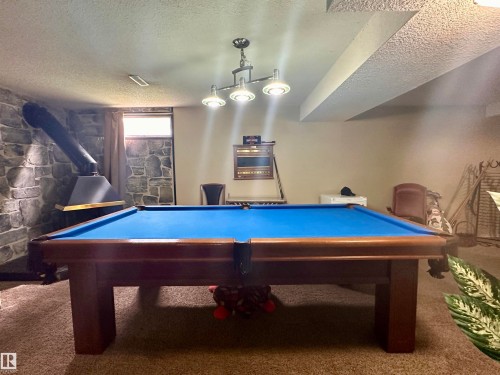 Recreation room featuring a wood-finish billiards table with blue felt and a three-light chandelier - 10619 108 Avenue, Westlock, AB - Indoor Photo Showing Other Room