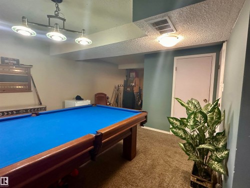 Recreation room with textured carpeting, a flush-mount ceiling light, and a dedicated hanging light fixture - 10619 108 Avenue, Westlock, AB - Indoor Photo Showing Other Room