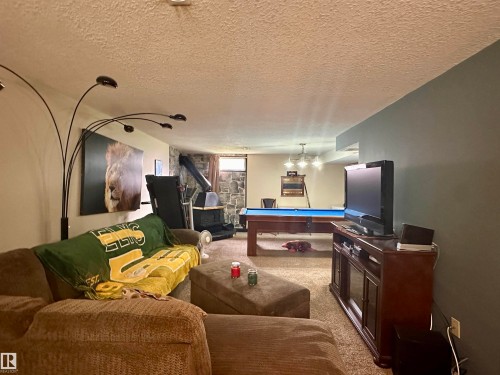 Recreation room featuring a stone-clad wall and a built-in wood stove - 10619 108 Avenue, Westlock, AB - Indoor Photo Showing Other Room