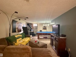Recreation room featuring a stone-clad wall and a built-in wood stove - 
