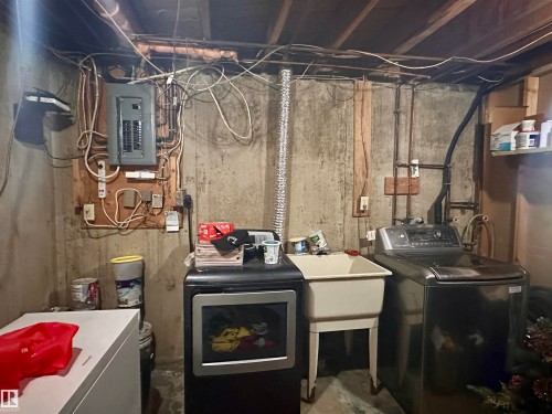 Basement utility area featuring exposed concrete walls, visible electrical panel, and overhead wood joists - 10619 108 Avenue, Westlock, AB - Indoor Photo Showing Laundry Room