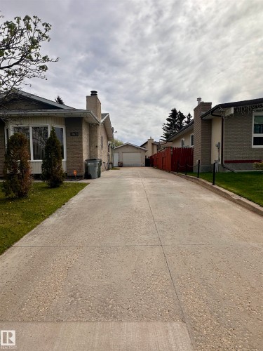 Long concrete driveway providing access to a detached garage with an overhead door - 10619 108 Avenue, Westlock, AB - Outdoor