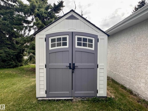 Outdoor storage shed with white siding and a dark gray shingle roof - 10619 108 Avenue, Westlock, AB - Outdoor