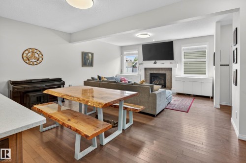 Open-concept living space with wood-finish flooring, a tile-surround fireplace, and multiple windows - 2007 72 Street, Edmonton, AB - Indoor With Fireplace