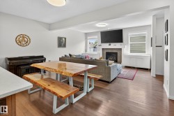 Open-concept living space with wood-finish flooring, a tile-surround fireplace, and multiple windows - 