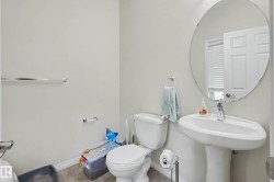 Powder room featuring a pedestal sink with a single-handle faucet, a circular mirror, and tile flooring - 