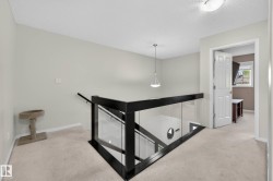 Contemporary glass and dark wood railing, neutral wall color, recessed lighting, and carpeted flooring - 