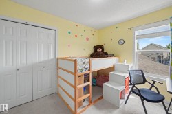 Bedroom featuring light yellow walls, white bi-fold closet doors, carpet flooring, and a white-framed window - 