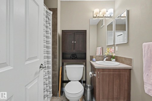 Bathroom featuring a wood-finish vanity with an integrated sink and backsplash, a three-light vanity fixture, and a wall-mounted medicine cabinet - 2007 72 Street, Edmonton, AB - Indoor Photo Showing Bathroom