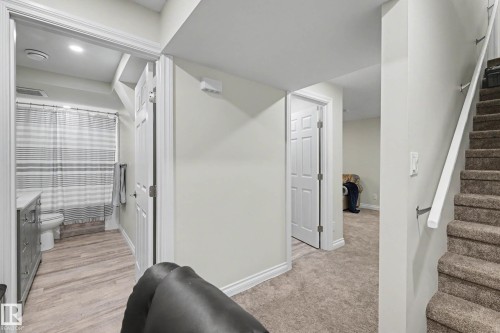 Carpeted stairway with white railing, leading to a hallway with wood-finish flooring and a white paneled door - 2007 72 Street, Edmonton, AB - Indoor Photo Showing Other Room