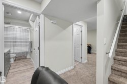 Carpeted stairway with white railing, leading to a hallway with wood-finish flooring and a white paneled door - 