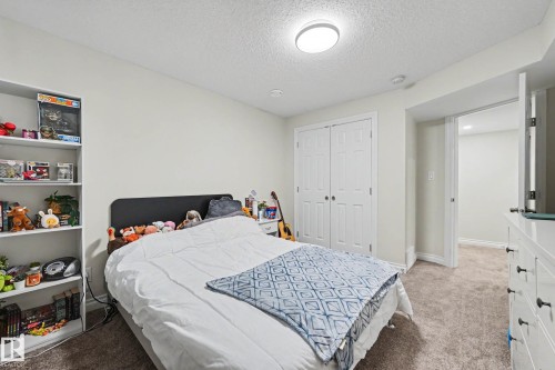 Carpeted bedroom featuring a flush-mount ceiling light, white bi-fold closet doors, and light-toned walls - 2007 72 Street, Edmonton, AB - Indoor Photo Showing Bedroom