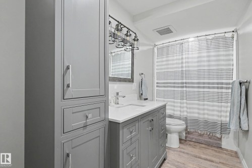 Contemporary bathroom featuring a gray shaker-style vanity with a white countertop and undermount sink - 2007 72 Street, Edmonton, AB - Indoor Photo Showing Bathroom