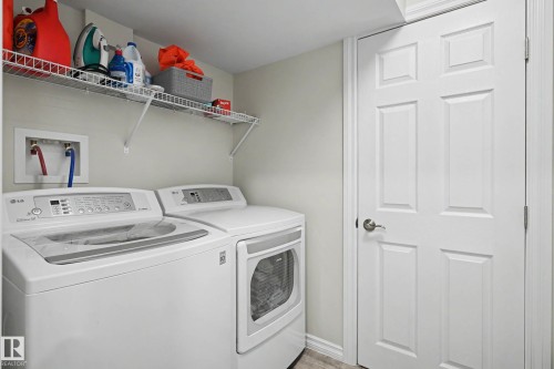 Dedicated laundry area featuring a washer and dryer, an overhead wire shelving unit, and a six-panel interior door - 2007 72 Street, Edmonton, AB - Indoor Photo Showing Laundry Room