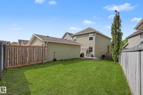 Expansive backyard featuring a manicured lawn, a wooden privacy fence, and a detached garage with light green siding - 2007 72 Street, Edmonton, AB - Outdoor With Exterior