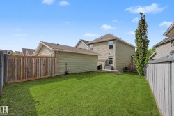 Expansive backyard featuring a manicured lawn, a wooden privacy fence, and a detached garage with light green siding - 