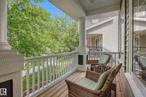 Covered front porch with wood-finish flooring, white spindle railing, and architectural columns - 2007 72 Street, Edmonton, AB - Outdoor With Deck Patio Veranda With Exterior