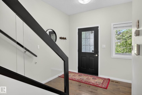 Foyer with wood-finish flooring, a black paneled door with decorative glass, and a white-framed window - 2007 72 Street, Edmonton, AB - Indoor Photo Showing Other Room