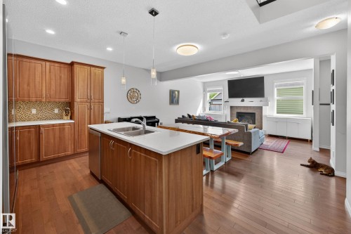 Kitchen island with double basin sink and stainless steel dishwasher - 2007 72 Street, Edmonton, AB - Indoor Photo Showing Kitchen With Fireplace With Double Sink