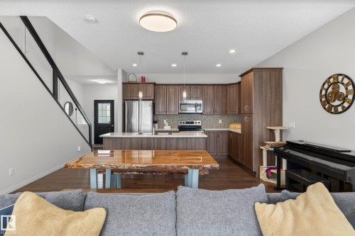 Open-concept living space featuring wood-finish flooring, a contemporary kitchen with stainless steel appliances, and a central island with a light-toned countertop - 2007 72 Street, Edmonton, AB - Indoor Photo Showing Kitchen