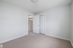 Spacious room featuring neutral carpet flooring, light-toned walls, white trim, a double bi-fold closet, and an overhead flush-mount light fixture - 