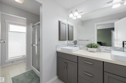 Dual vessel sinks set on an extended vanity with gray cabinetry and a light-toned countertop - 