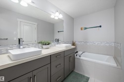 Dual vessel sinks set atop a vanity with dark gray cabinetry and a light-toned countertop - 