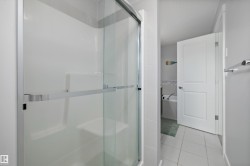 Glass-enclosed shower with brushed metal hardware, white subway tile surround, and built-in shelving - 