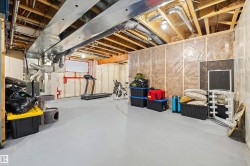 Expansive unfinished basement featuring exposed ceiling joists, overhead ductwork, and partial wall insulation - 