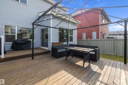 Expansive wood deck with a black metal frame pergola and string lighting - 