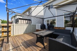 Expansive wood-finish deck featuring a black metal gazebo frame with integrated string lighting - 