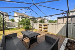Expansive backyard featuring a wood deck, perimeter fencing, a built-in planter box, and a metal pergola frame - 