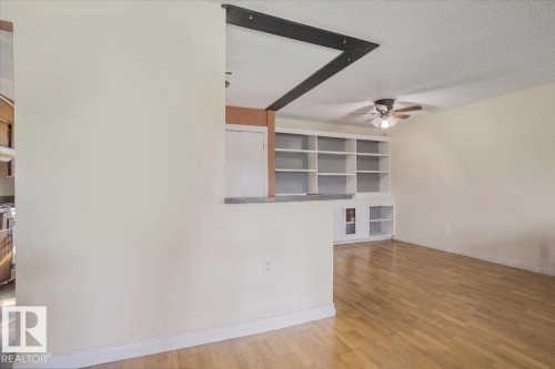 Living area featuring light wood-finish flooring, a ceiling fan, and built-in shelving - 13224 37 Street, Edmonton, AB 