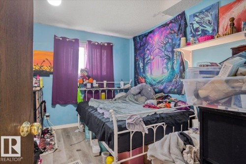 Wood-finish flooring with light blue walls and a window featuring purple drapes - 13224 37 Street, Edmonton, AB 