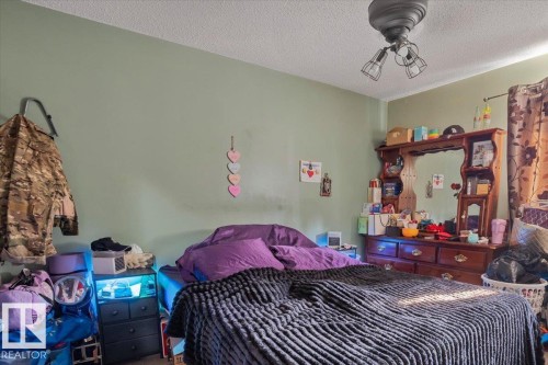 Bedroom featuring a ceiling-mounted light fixture, light green wall paint, and window with patterned drapes - 13224 37 Street, Edmonton, AB 