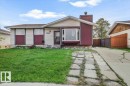 Front exterior featuring light-colored siding with dark red accents, a prominent bay window, and a concrete driveway - 13224 37 Street, Edmonton, AB 