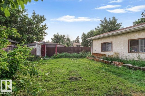 Expansive backyard featuring a partial stucco exterior, a wood privacy fence, and two storage sheds - 13224 37 Street, Edmonton, AB 
