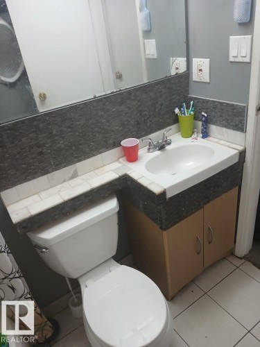 Bathroom featuring a white toilet, integrated sink, and wood-finish vanity - 13224 37 Street, Edmonton, AB 