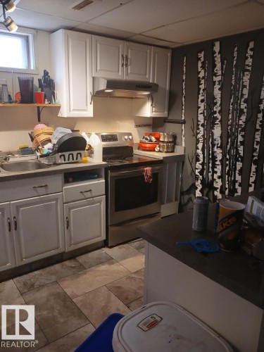 Kitchen featuring white cabinetry, a stainless steel range, and tile flooring - 13224 37 Street, Edmonton, AB 
