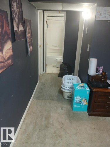 Bathroom featuring a white tub and toilet, white floor tiling, and a white framed doorway - 13224 37 Street, Edmonton, AB 