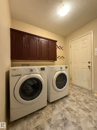 Dedicated laundry space featuring resilient flooring, overhead cabinetry, and recessed lighting - 1764 Melrose Crescent, Edmonton, AB 