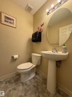 Pedestal sink with chrome faucet, circular wall mirror, and vanity lighting - 