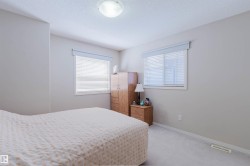 Carpeted room featuring multiple windows with blinds, a ceiling-mounted light fixture, and neutral wall paint - 
