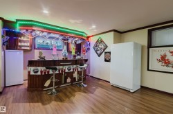 Custom wood-finish bar with integrated cabinetry and overhead stemware rack, recessed lighting, wood-finish flooring, and crown molding - 